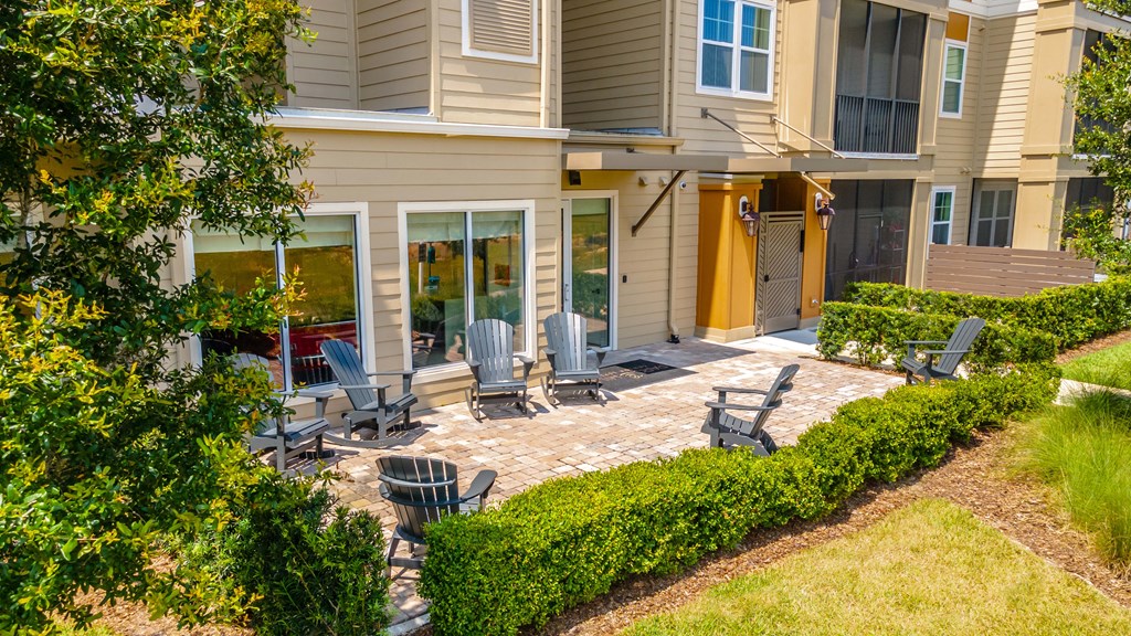 a patio with chairs and a firepit in front of a house