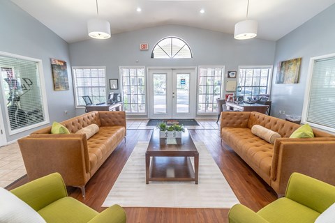 A living room with a brown couch and green chairs.