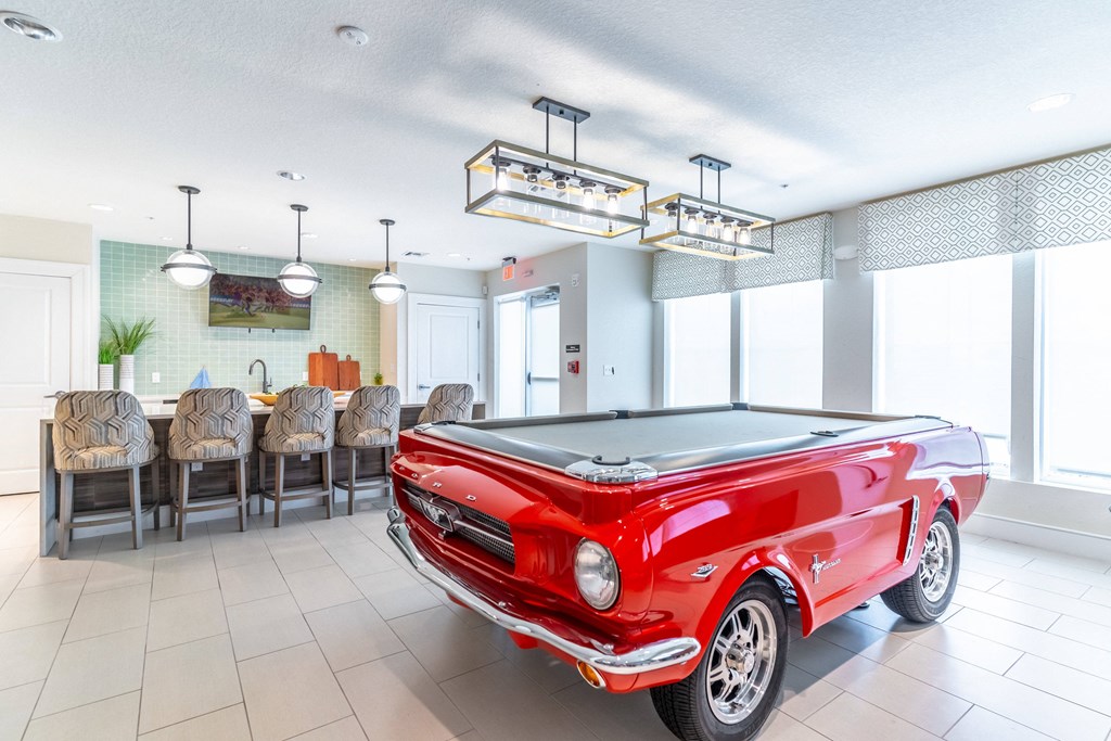 a game room with a pool table and a red car