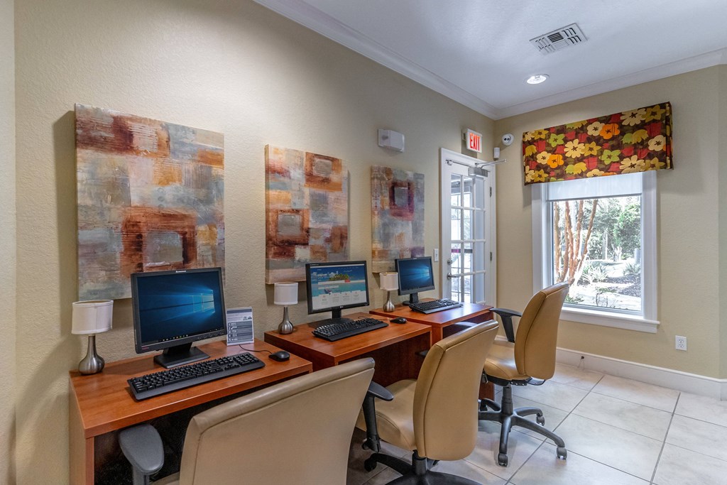 a home office with three computers on a wooden desk