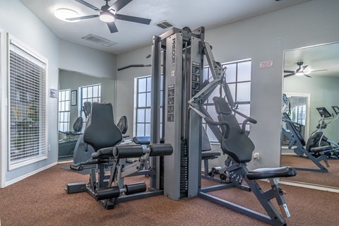 A gym with a weight machine and a fan.