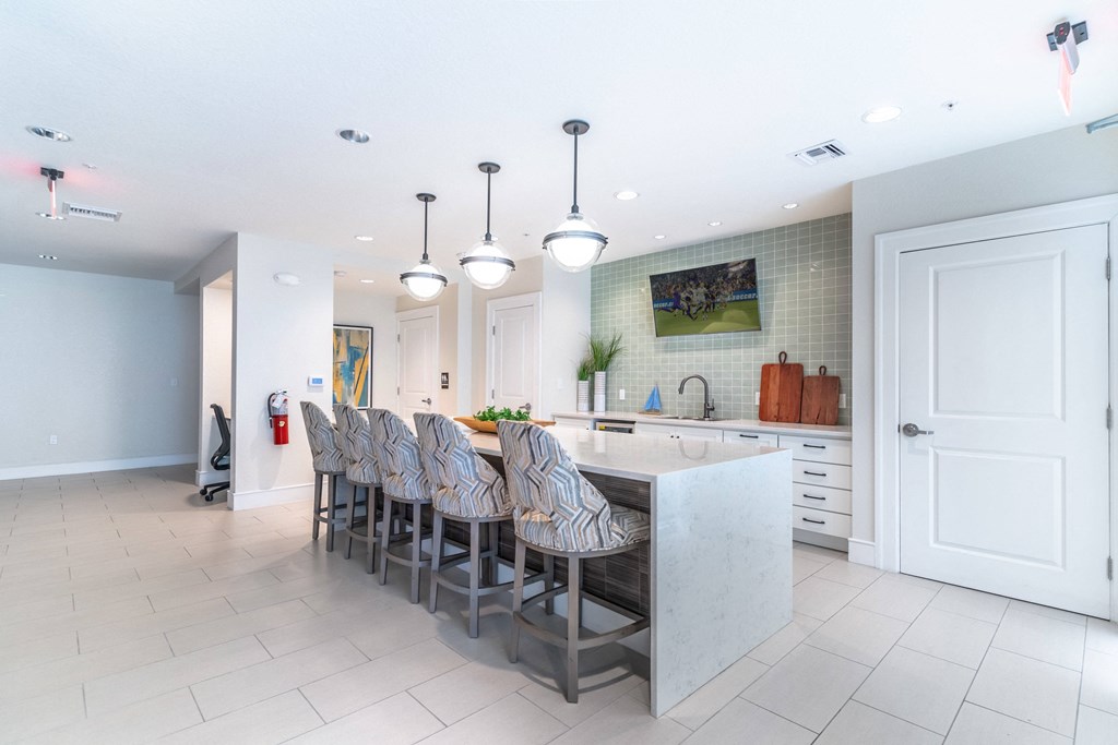 a large white kitchen with a long island and chairs