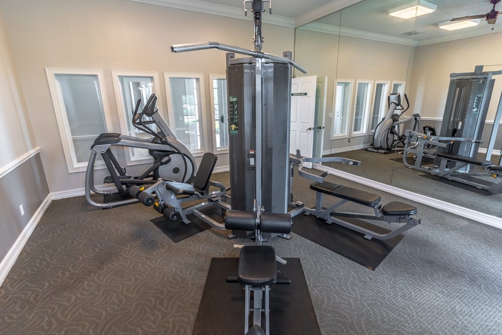 A gym with a variety of equipment including a treadmill, a stationary bike, and a leg press machine.