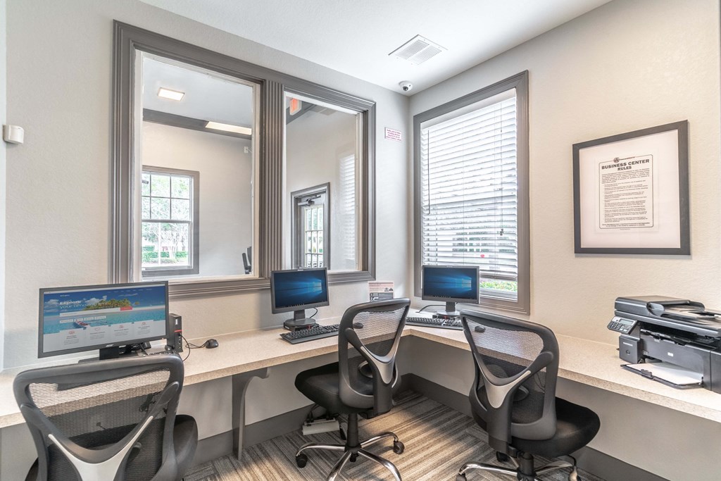 three computer desks in a room with chairs and a printer