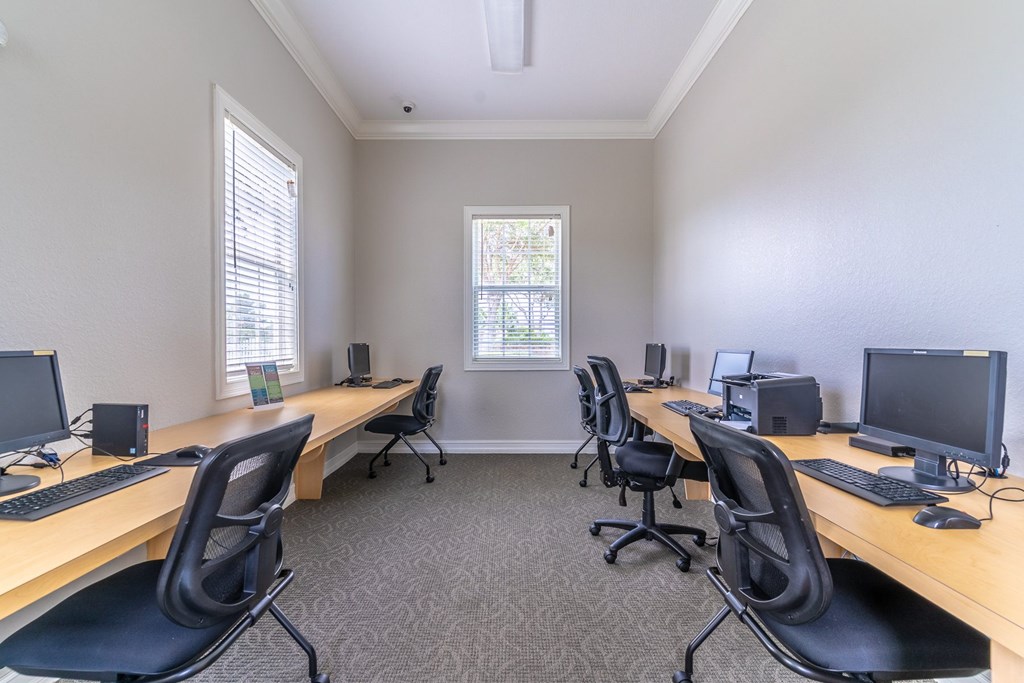 A room with a desk and chairs with a window in the background.