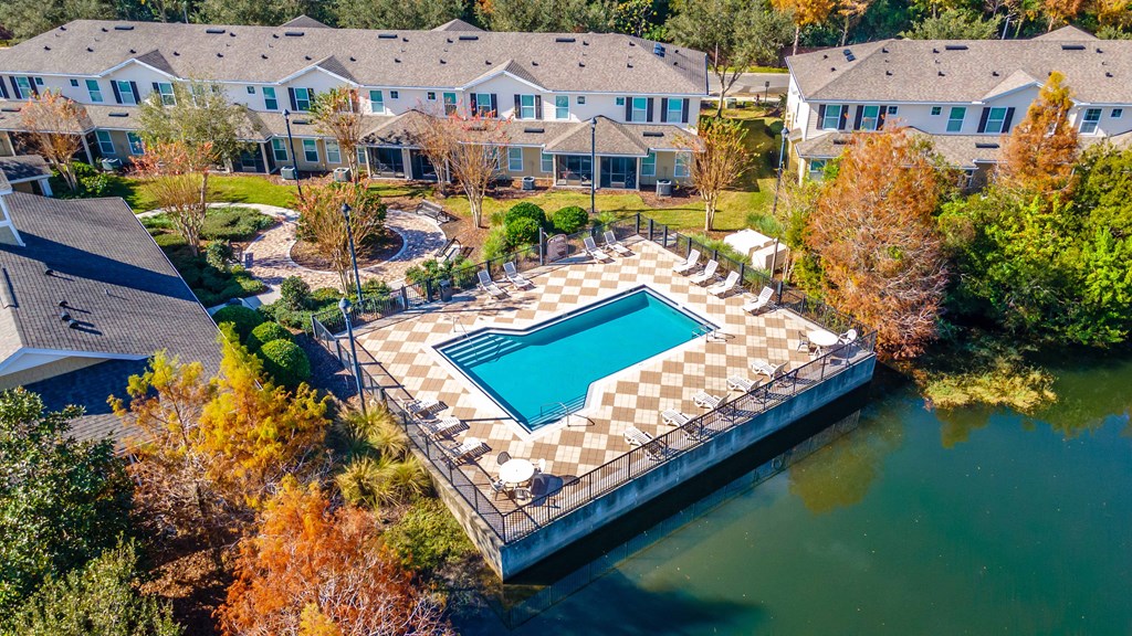An aerial view of a pool surrounded by a fence and trees.