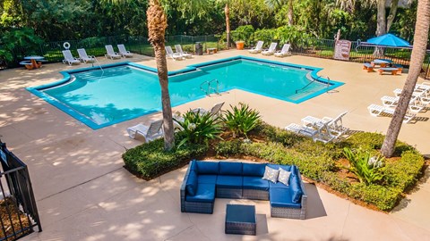 A pool area with a blue couch and chairs.