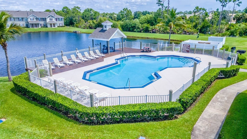 A pool surrounded by a white fence and a small gazebo.