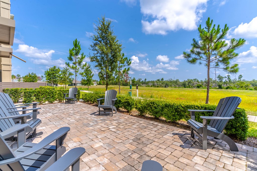a patio with chairs and trees in the background
