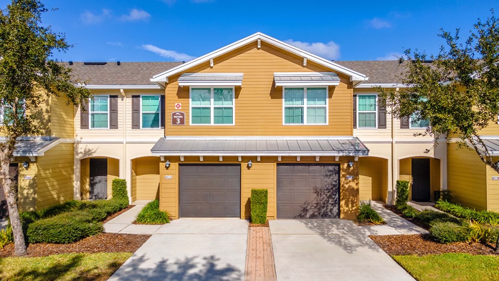 A yellow house with a garage door and a driveway.