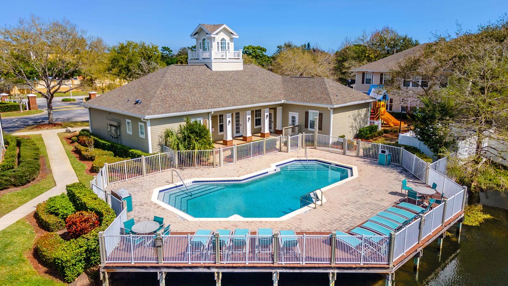 a large pool in front of a house with a deck and a pool house