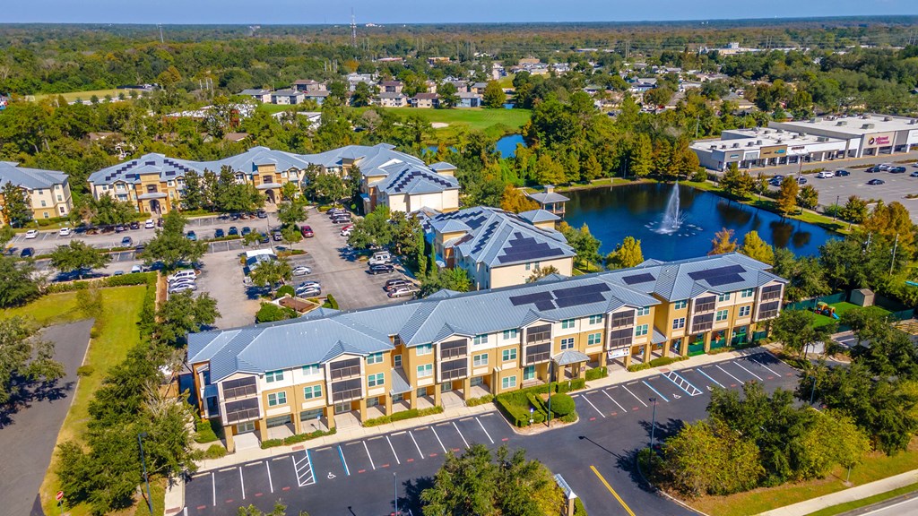 A large building complex with a fountain in the middle of a pond.