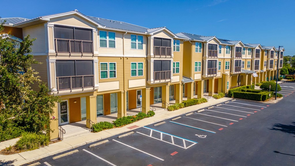 A row of apartment buildings with a parking lot in front.