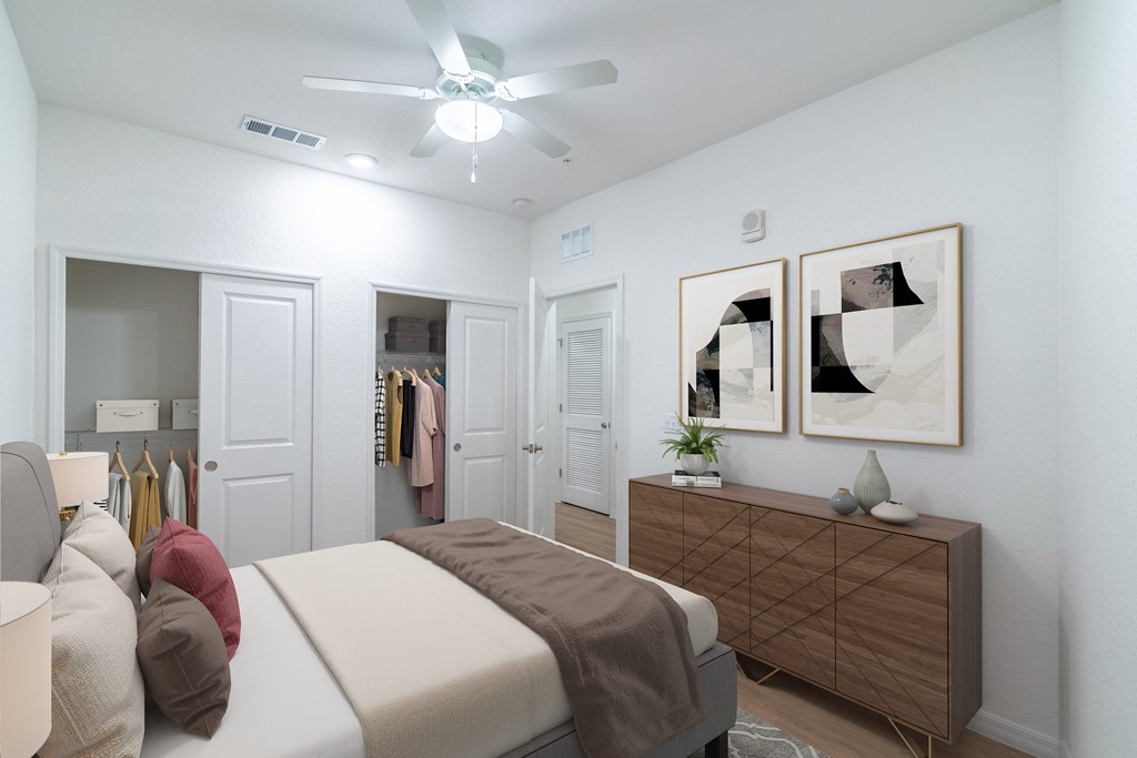 A bedroom with a bed, a dresser, and a ceiling fan.