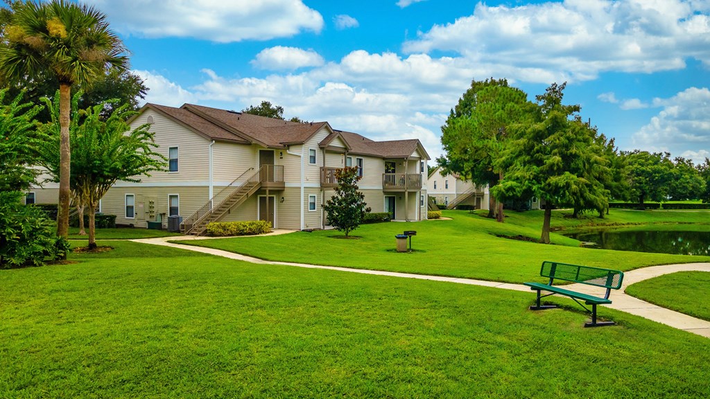 A green park with a bench and a building in the background.