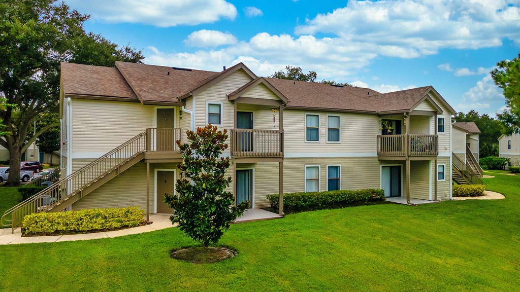 A large two-story apartment building with a green lawn in front.