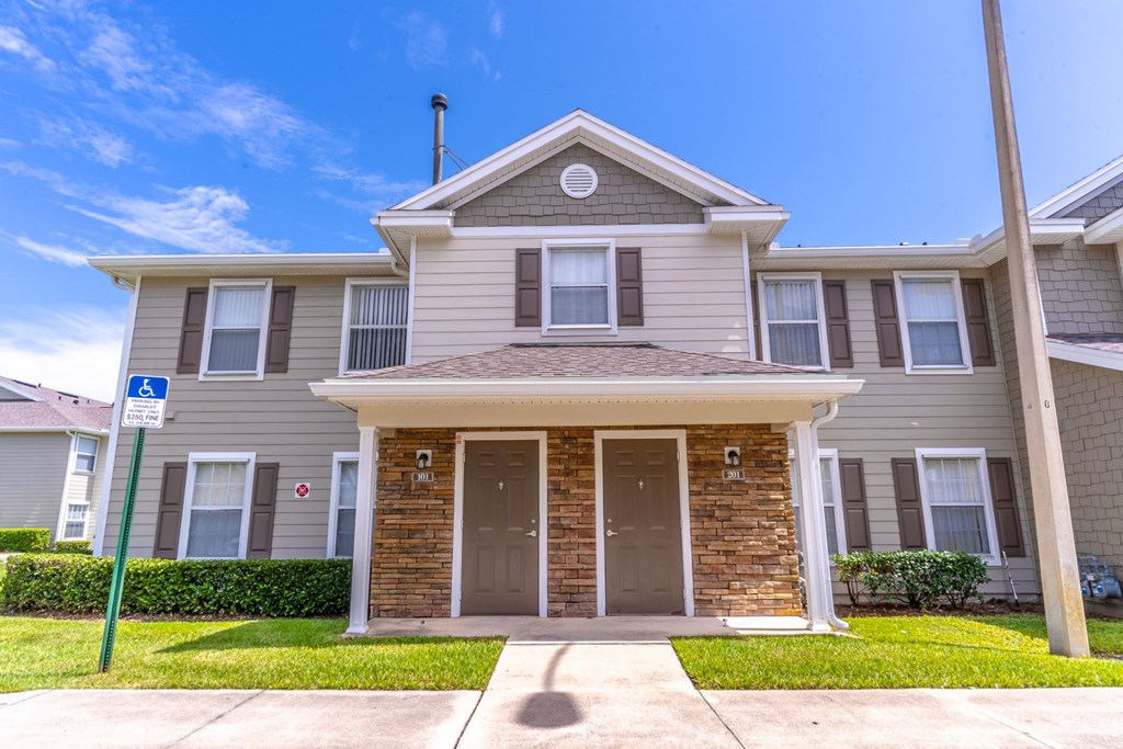 A two-story house with a brown door and a handicap sign in front.