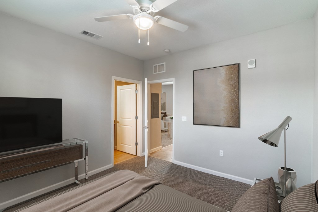 a living room with a ceiling fan and a tv