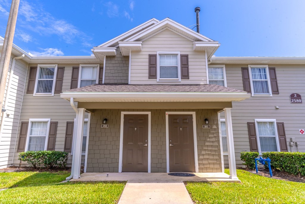 A two-story house with a front porch and a brown door.
