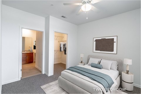 A bedroom with a bed, two lamps, and a ceiling fan.