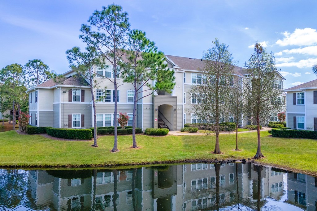 an apartment building with a pond in front of it