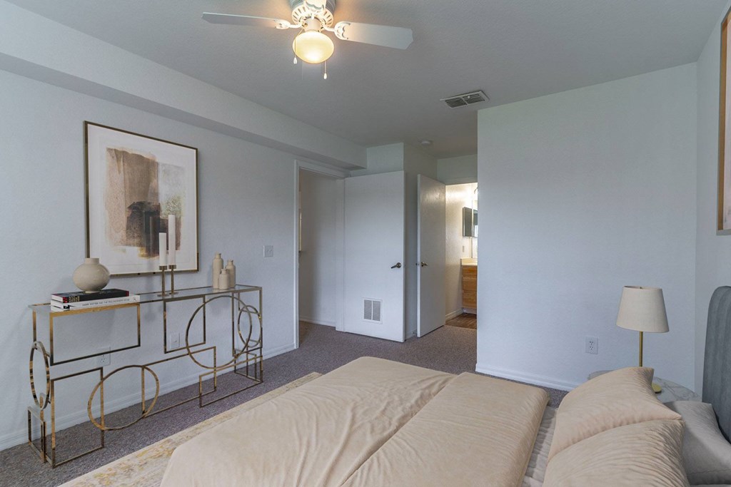 A bedroom with a bed, a table with a lamp and a painting on the wall.