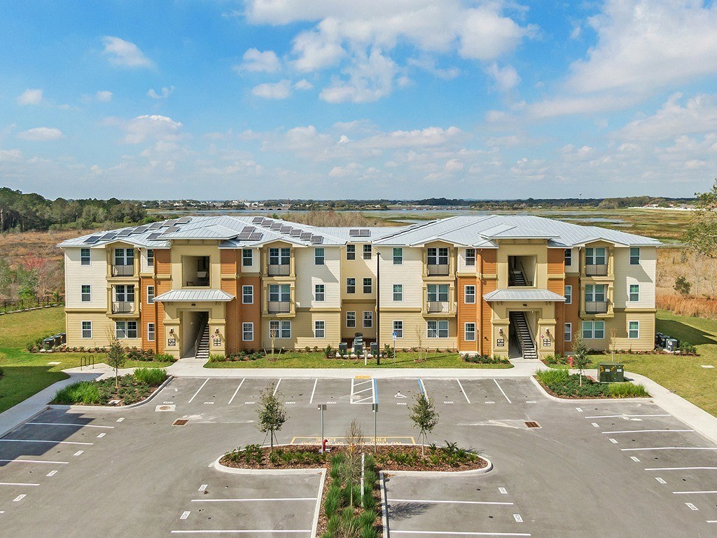 an exterior view of an apartment building in a parking lot