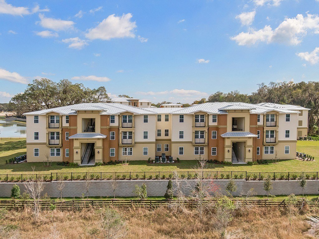 an aerial view of a large apartment building with a grassy field and a lake