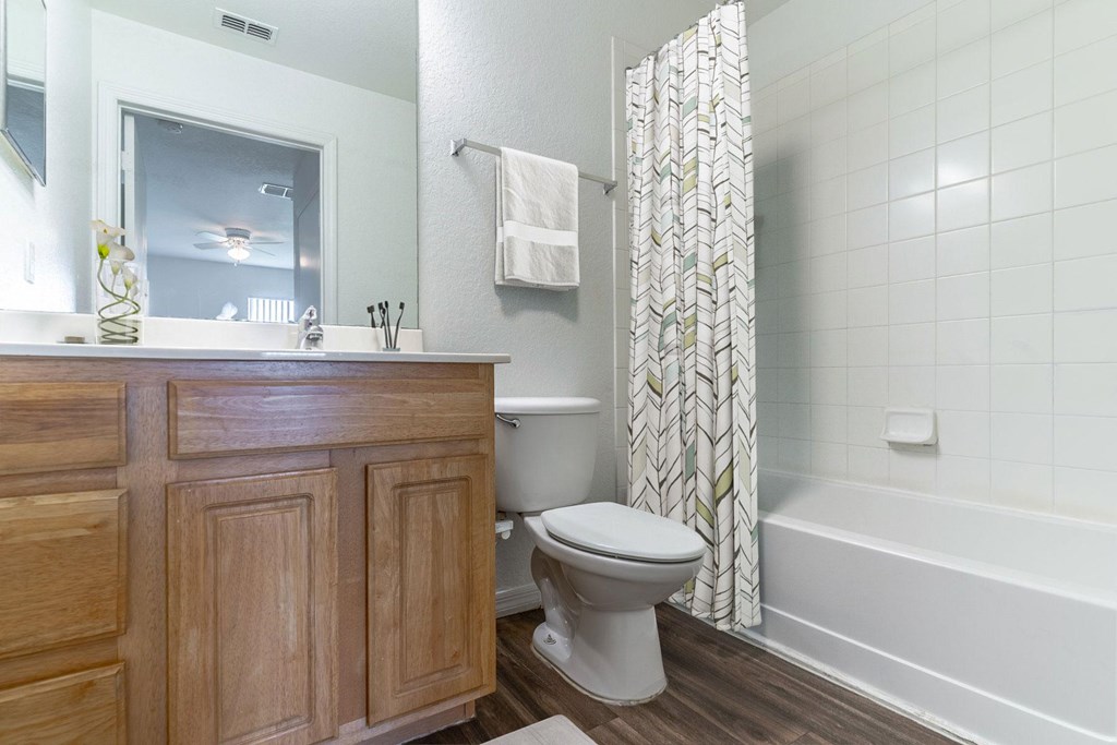 A white toilet sits next to a wooden cabinet in a bathroom.