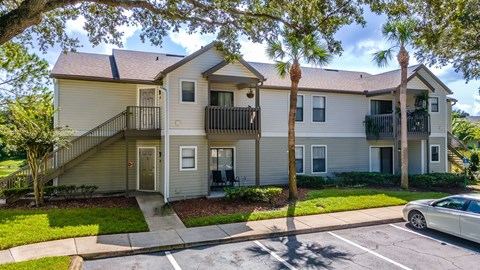 A two-story apartment building with a car parked in front.