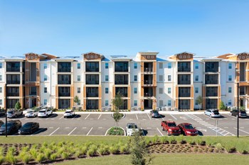 an apartment complex with a parking lot in front of it - Photo Gallery 5