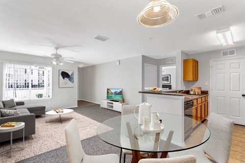 a living room with a glass table and a kitchen