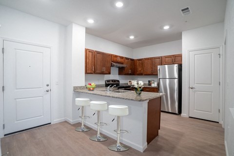 a kitchen with a large island with bar stools and a stainless steel refrigerator