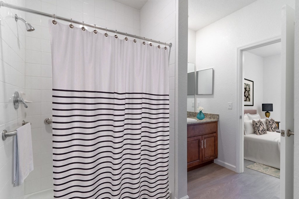 a bathroom with a shower curtain and a sink and a bedroom