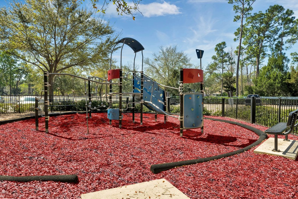 a playground with a slide and red mulch
