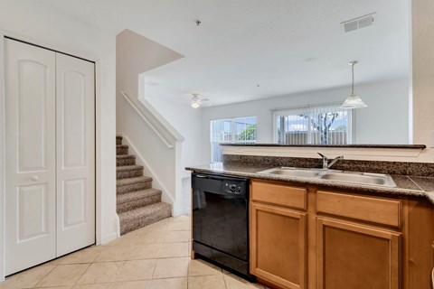 a kitchen with a sink and a dishwasher next to a staircase