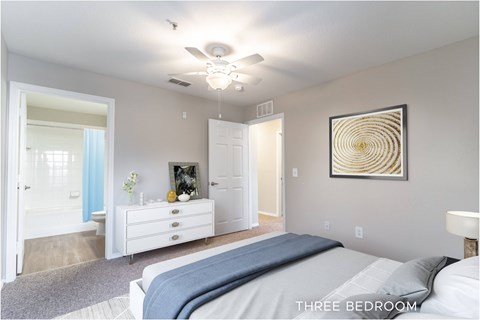 A bedroom with a bed, dresser, and ceiling fan.