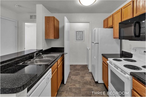 A kitchen with a white refrigerator and black countertops.