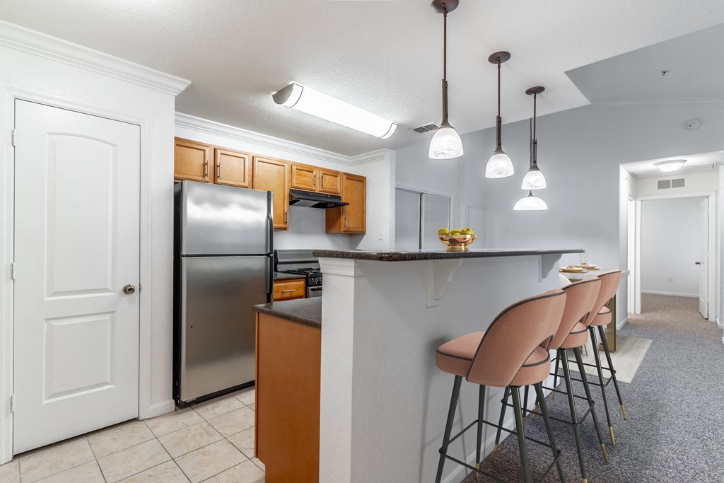 a kitchen with a bar with chairs and a refrigerator