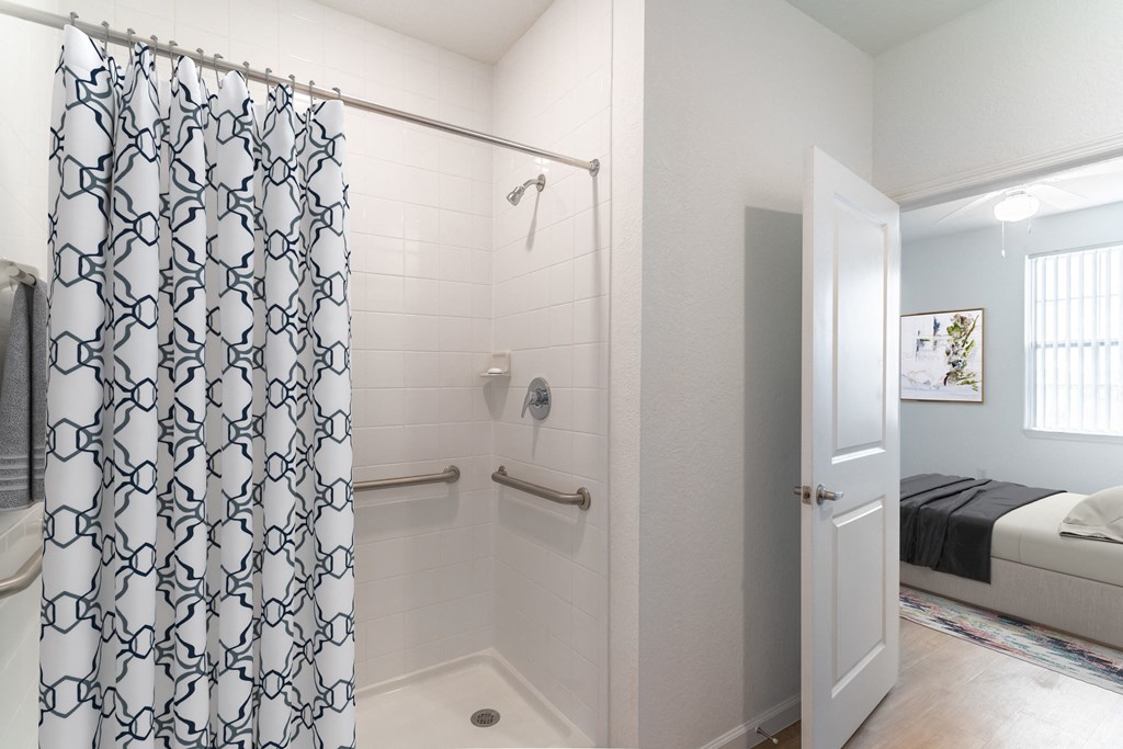 a bathroom with a shower and a bed in a room
