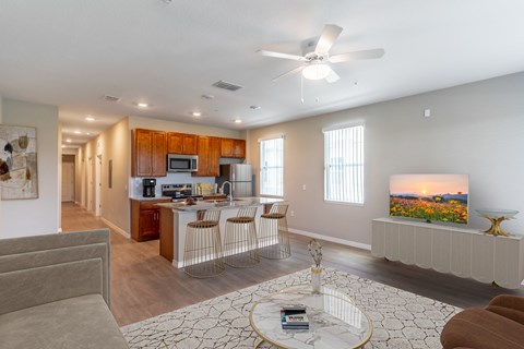 a living room with a kitchen and a ceiling fan