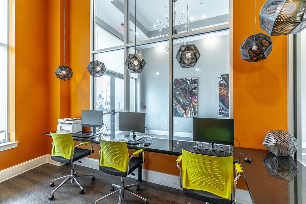 an office with orange walls and a black desk with yellow chairs