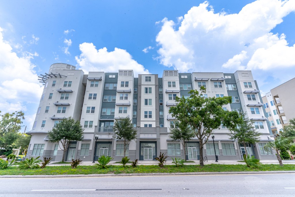 a story apartment building with trees in front of it and a blue sky in the background