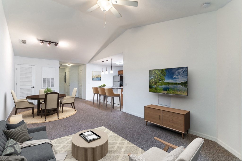 a living room with a tv and a dining room in the background