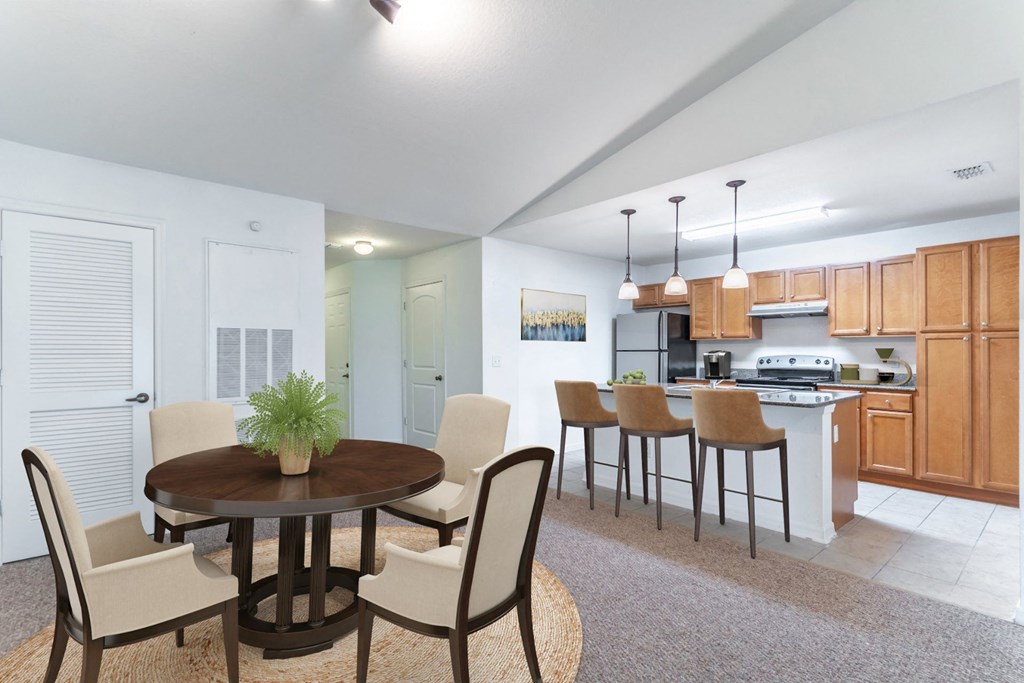 a dining area with a table and chairs and a kitchen in the background