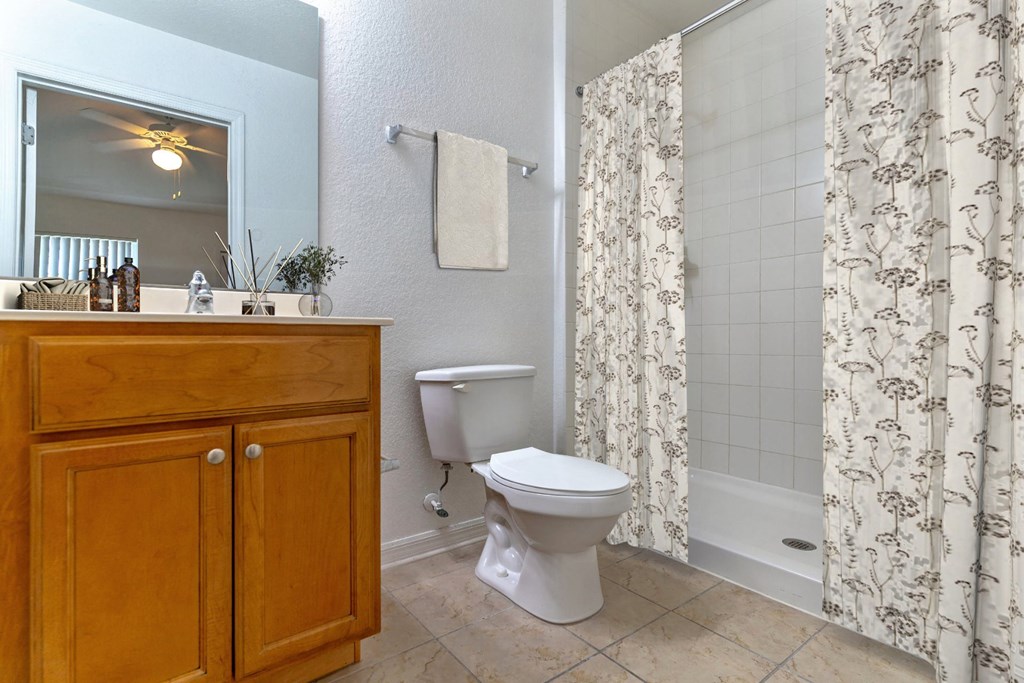 a bathroom with a white toilet next to a bathtub with a shower curtain