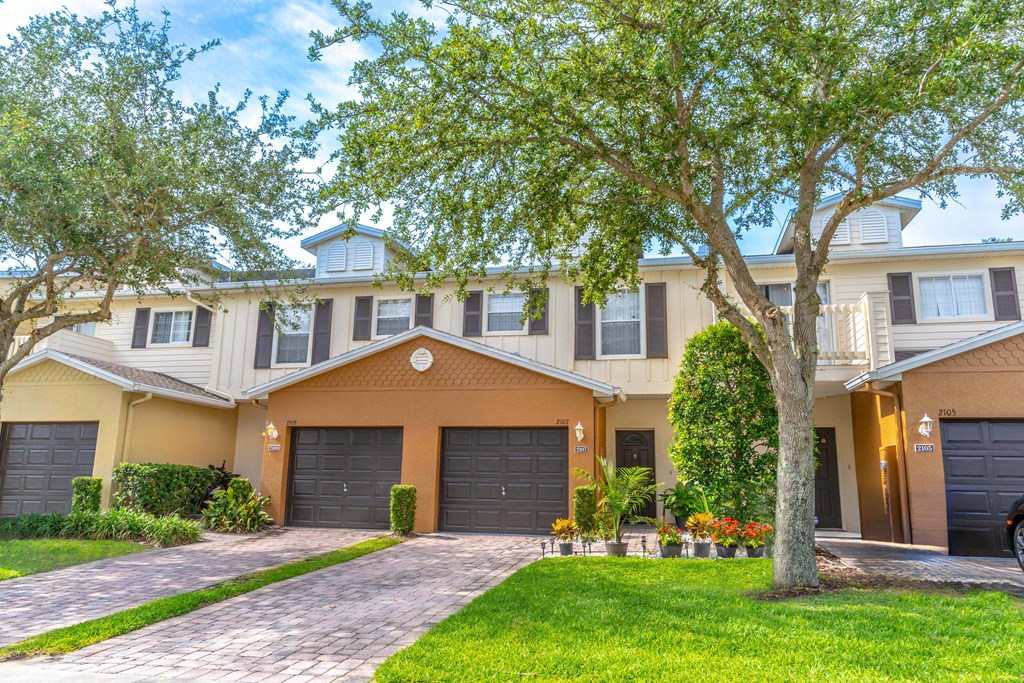 a townhome with two garages and a tree in front of it