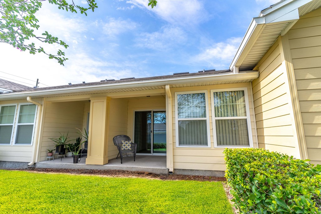 a patio in front of a yellow house with a blue sky in the background