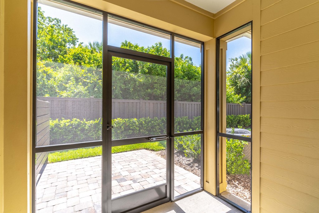 a large sliding glass door opens to a patio with a brick walkway