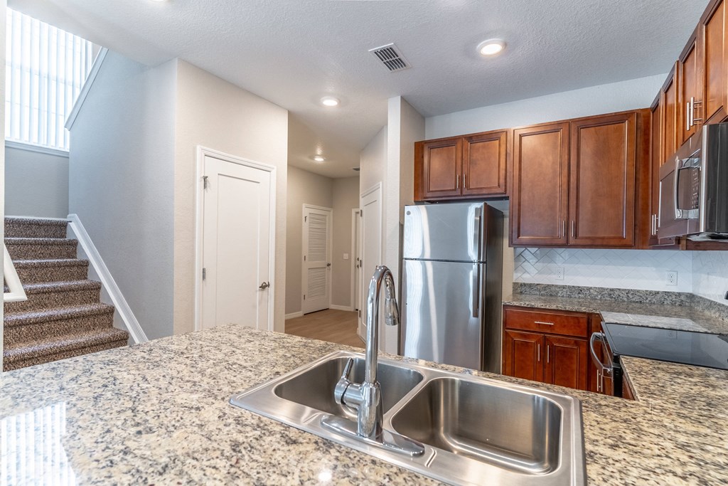 a kitchen with granite countertops and a stainless steel refrigerator